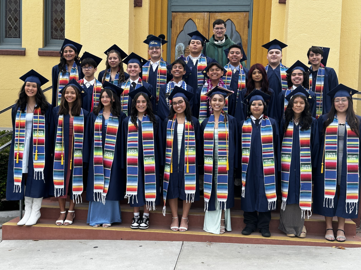 Our Lady's School Class of 2025 standing infront of the school building main door, standing on the steps with their teacher standing behind them