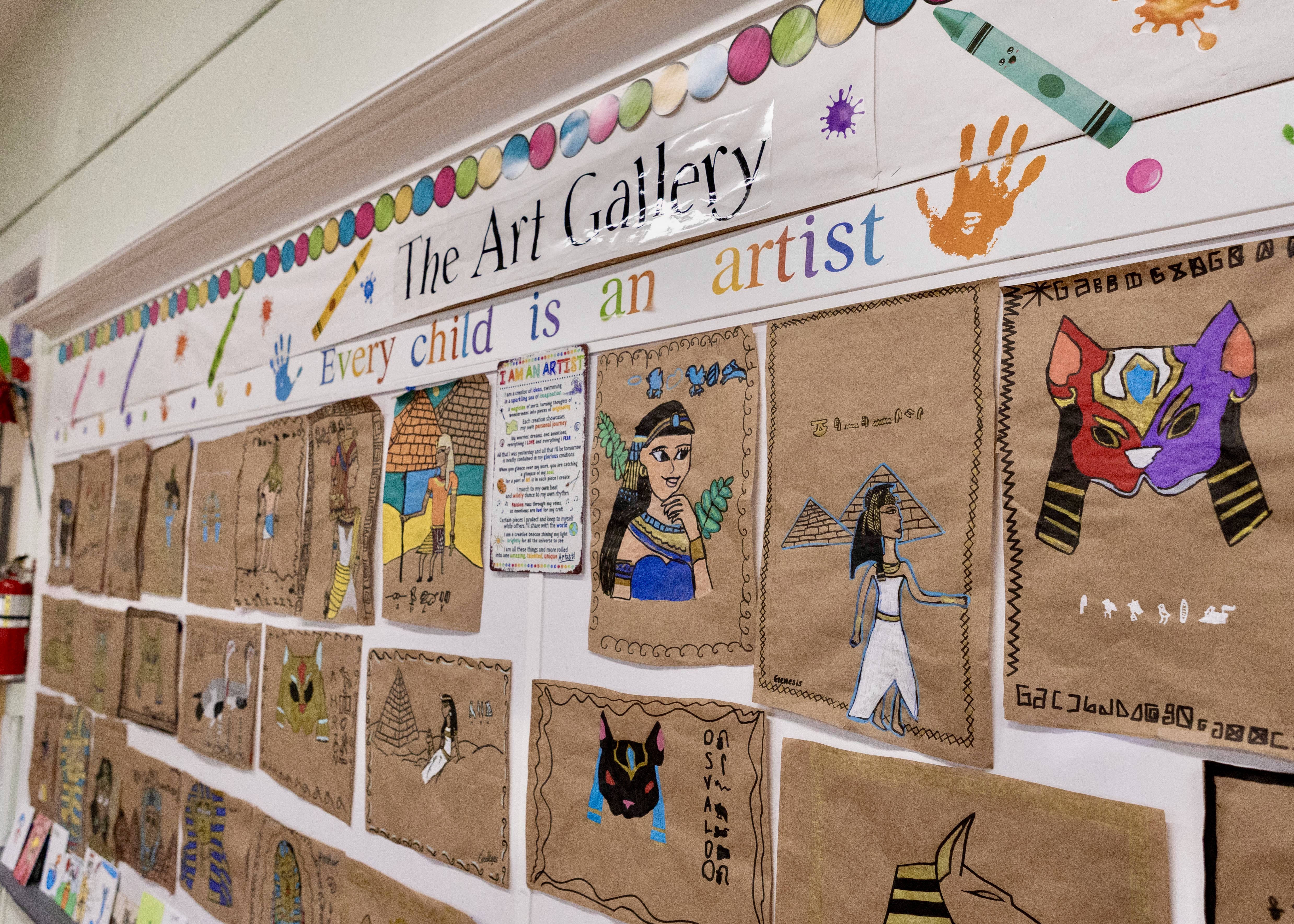 Art gallery wall displaying colorful student artwork with text 'Every child is an artist' exemplifying student creative work.