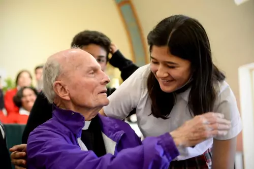 A female student smiling and listing to and older father talking